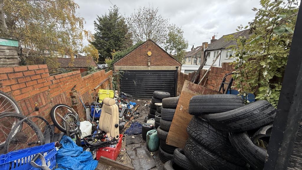Lot: 26 - FREEHOLD GARAGE AND YARD WITH POWER LIGHTING AND GATED FRONTAGE - External image of garage through gates